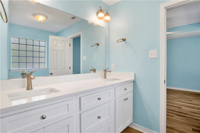 bathroom with double vanity, a sink, and baseboards