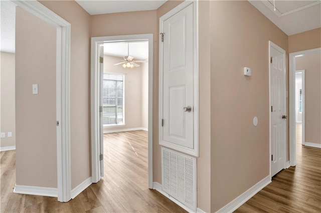 corridor featuring attic access, wood finished floors, visible vents, and baseboards