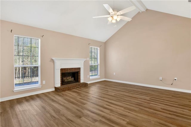 unfurnished living room with a wealth of natural light, a brick fireplace, beamed ceiling, and wood finished floors