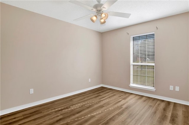 spare room with ceiling fan, a textured ceiling, wood finished floors, and baseboards