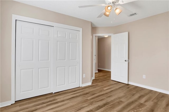 unfurnished bedroom with baseboards, visible vents, ceiling fan, wood finished floors, and a closet