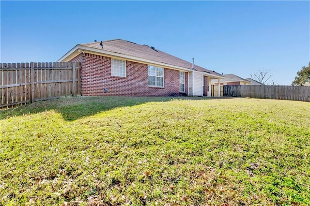 rear view of house featuring brick siding, a lawn, and a fenced backyard