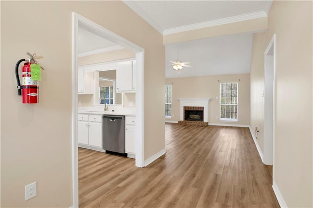 interior space featuring ornamental molding, a sink, light wood-style flooring, and baseboards