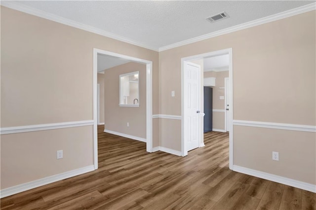 unfurnished room with visible vents, a textured ceiling, baseboards, and wood finished floors