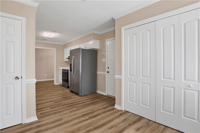 kitchen with light wood-style flooring, ornamental molding, white cabinetry, stainless steel fridge, and range