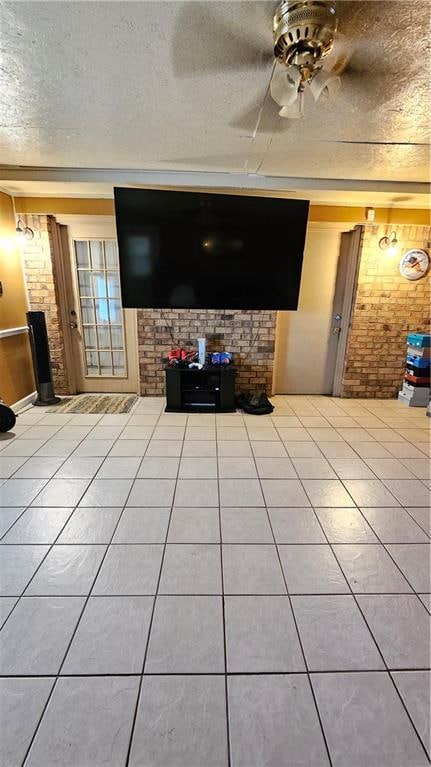 unfurnished living room with light tile floors, brick wall, and ceiling fan