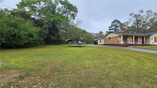 view of yard featuring a porch and a trampoline