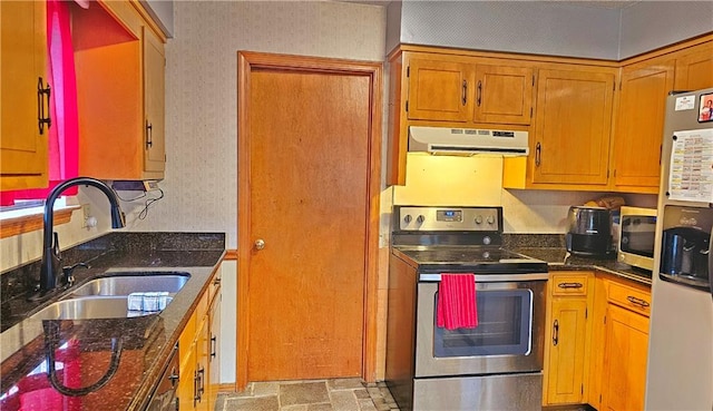 kitchen featuring sink, light tile floors, stainless steel appliances, and dark stone countertops