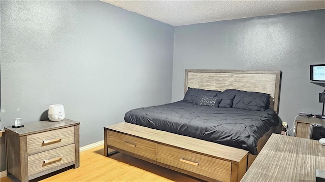 bedroom with a textured ceiling and light wood-type flooring