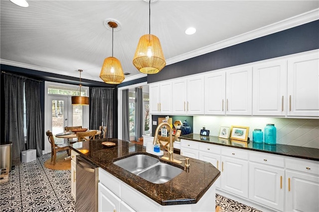 kitchen featuring white cabinetry, stainless steel dishwasher, a kitchen island with sink, and dark stone countertops