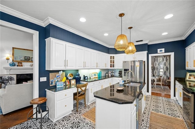 kitchen featuring appliances with stainless steel finishes, sink, white cabinets, and a kitchen island with sink