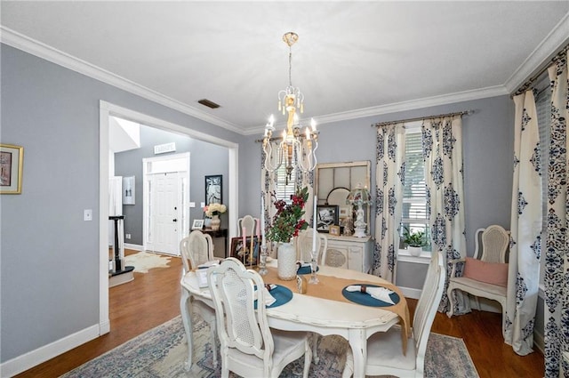 dining area with hardwood / wood-style floors, ornamental molding, and an inviting chandelier