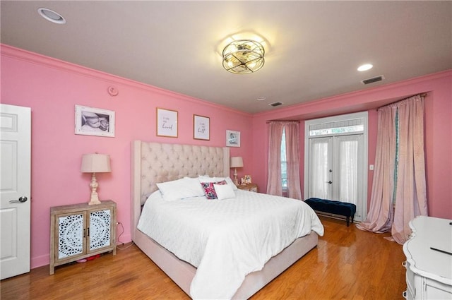 bedroom featuring wood-type flooring, ornamental molding, and french doors