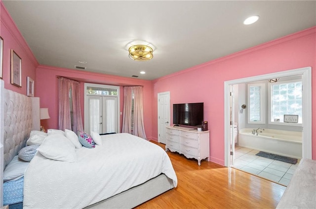 bedroom with french doors, crown molding, light hardwood / wood-style flooring, and ensuite bath