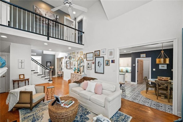 living room featuring ceiling fan, light hardwood / wood-style floors, and a high ceiling