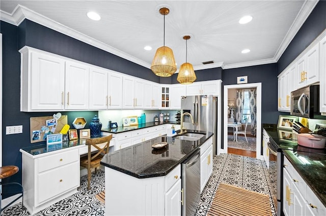 kitchen featuring decorative light fixtures, white cabinetry, stainless steel appliances, sink, and a center island with sink