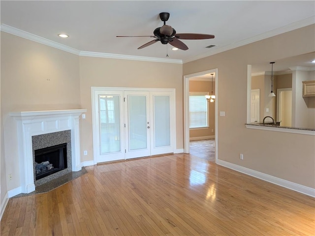 unfurnished living room with visible vents, baseboards, a fireplace with flush hearth, crown molding, and light wood-style floors