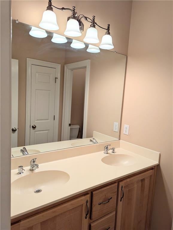 bathroom featuring double vanity, a sink, and toilet