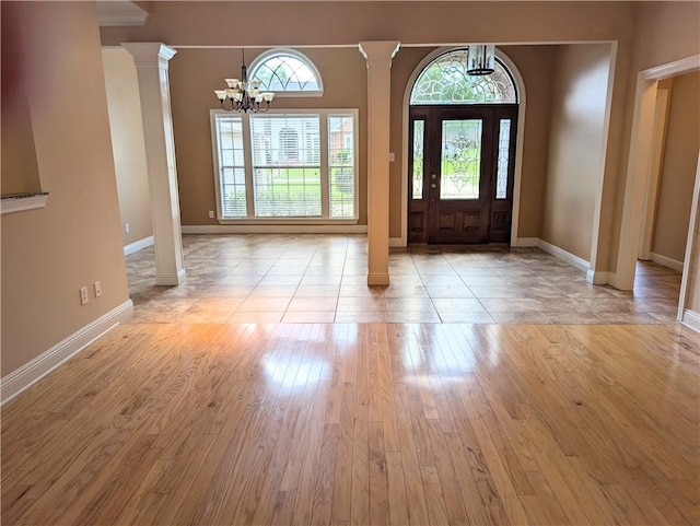 entryway featuring light wood finished floors, decorative columns, baseboards, and a notable chandelier