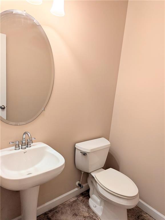 bathroom featuring toilet, baseboards, and a sink