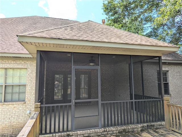 doorway to property with a shingled roof, ceiling fan, and brick siding