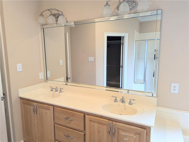 bathroom featuring double vanity, a shower with door, and a sink