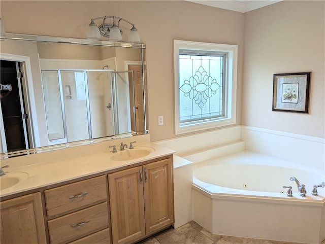 bathroom featuring double vanity, a stall shower, tile patterned floors, a garden tub, and a sink