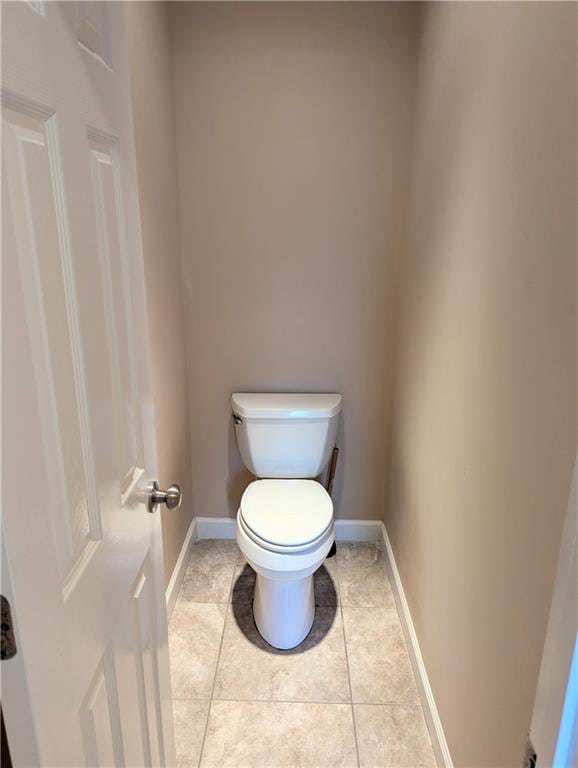 bathroom with tile patterned flooring, baseboards, and toilet