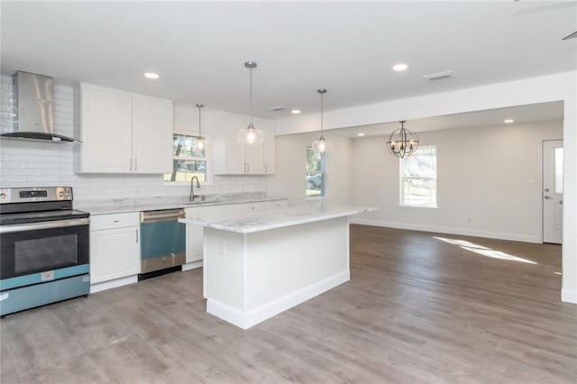 kitchen featuring stainless steel appliances, white cabinetry, a center island, and wall chimney range hood