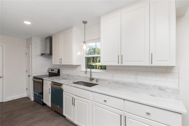 kitchen with appliances with stainless steel finishes, decorative light fixtures, sink, white cabinets, and wall chimney range hood