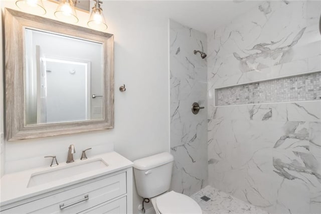 bathroom featuring vanity, toilet, and tiled shower