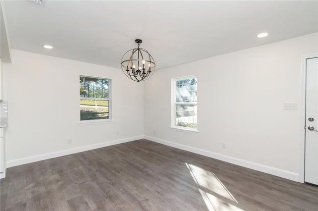 empty room with dark wood-type flooring and a chandelier