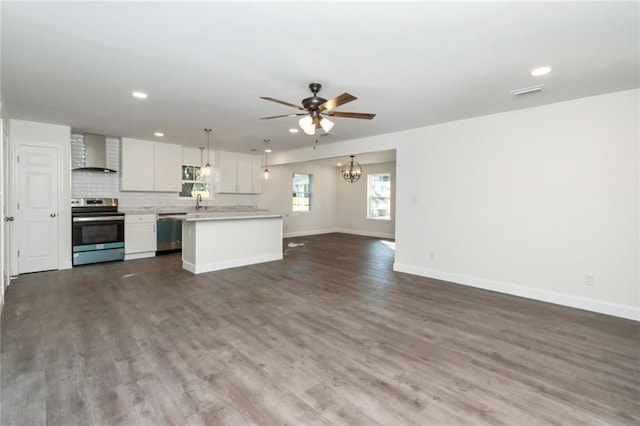 kitchen featuring pendant lighting, backsplash, stainless steel appliances, white cabinets, and wall chimney exhaust hood