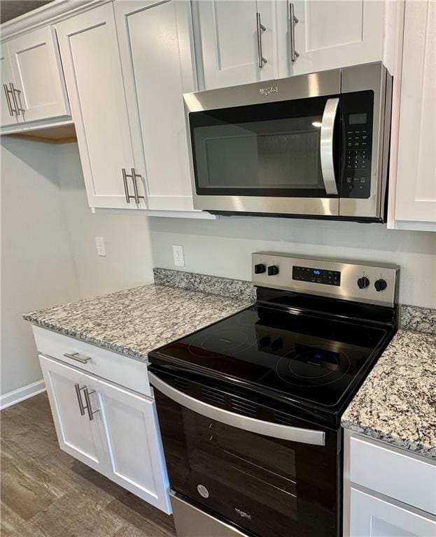 kitchen with stainless steel appliances, light stone countertops, and white cabinets