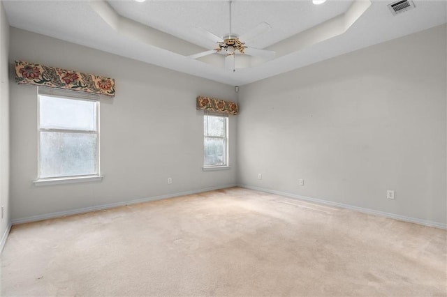 carpeted spare room featuring ceiling fan and a tray ceiling