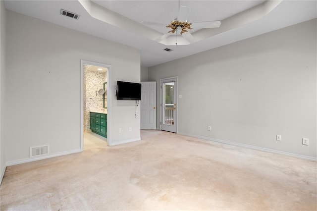 carpeted spare room with a tray ceiling and ceiling fan