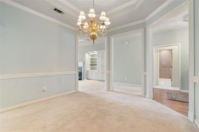 carpeted empty room featuring crown molding, an inviting chandelier, and a tray ceiling