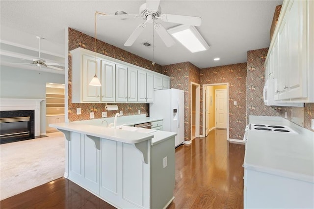 kitchen featuring a breakfast bar, kitchen peninsula, ceiling fan, white refrigerator with ice dispenser, and white cabinets