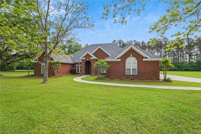 view of front of home with brick siding, a shingled roof, and a front lawn