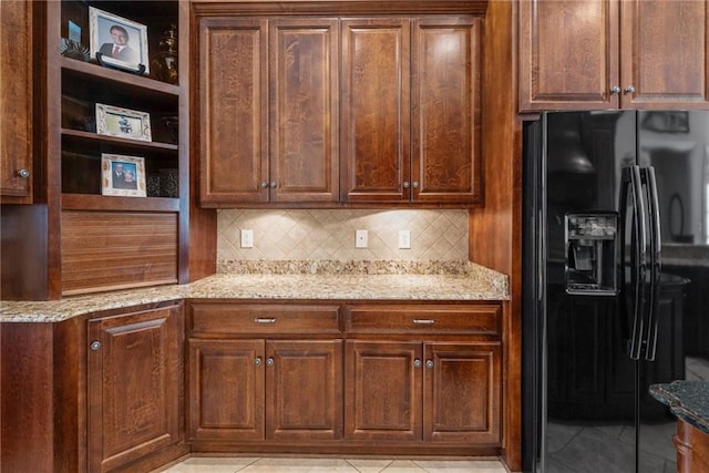 kitchen with backsplash, open shelves, black refrigerator with ice dispenser, light stone countertops, and light tile patterned floors