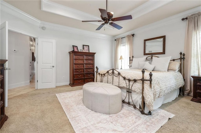 bedroom featuring light carpet, a ceiling fan, a tray ceiling, and crown molding