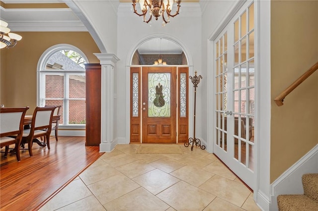 foyer entrance featuring stairs, ornamental molding, baseboards, and a notable chandelier