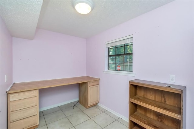 unfurnished office featuring built in desk, a textured ceiling, and light tile patterned flooring