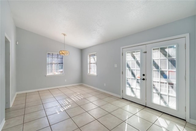 interior space featuring lofted ceiling, french doors, light tile patterned flooring, and a textured ceiling