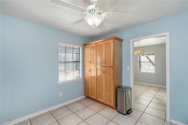 unfurnished bedroom with ceiling fan, a textured ceiling, and light tile patterned flooring