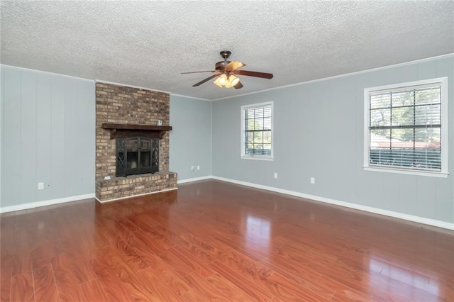 unfurnished living room featuring a brick fireplace, hardwood / wood-style floors, ceiling fan, and a wealth of natural light