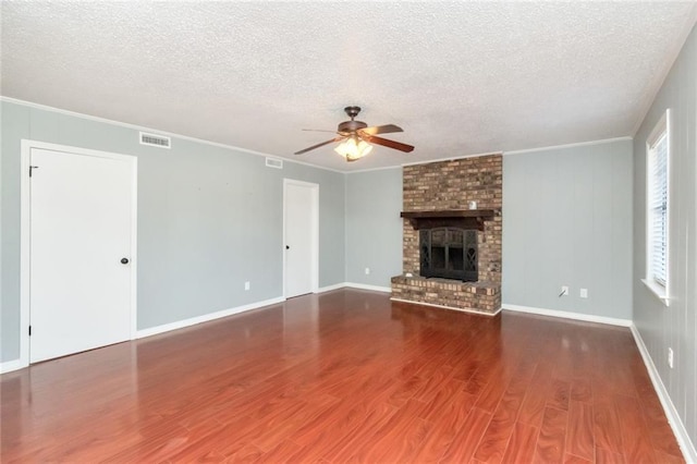 unfurnished living room with ceiling fan, a textured ceiling, dark hardwood / wood-style floors, a fireplace, and crown molding