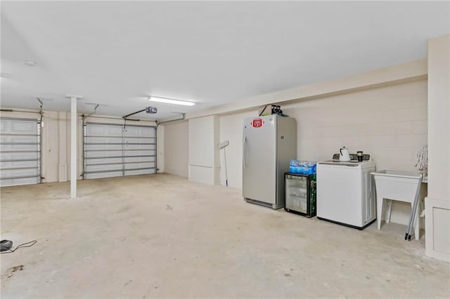 311 Magnolia Ave Unit 54, Satsuma, AL 36572 - garage with freestanding refrigerator, a garage door opener, wine cooler, washer / dryer, and fridge