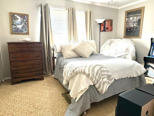 bedroom with crown molding and light carpet