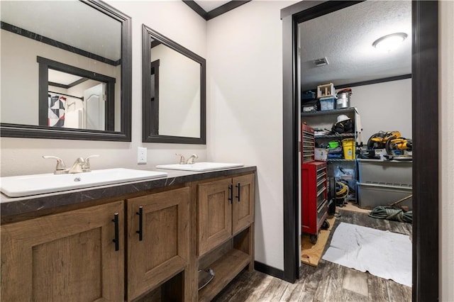 bathroom featuring a textured ceiling, dual vanity, and wood-type flooring